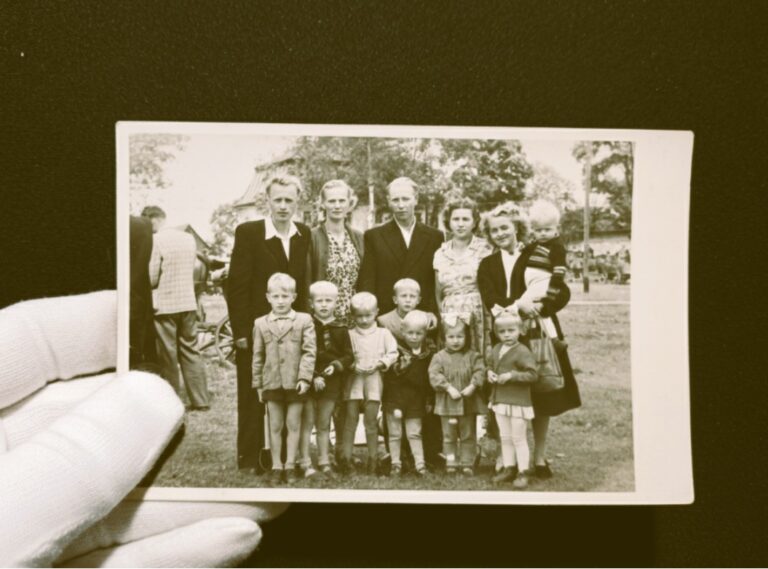 Prawidłowe trzymanie archiwalnej fotografii w białej bawełnianej rękawiczce na ciemnym tle – poradnik domowego archiwisty Tradicon