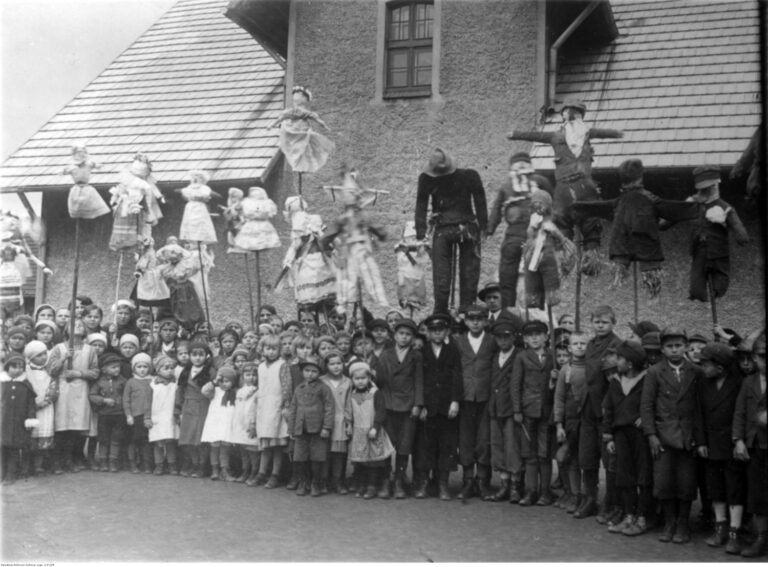 Archiwalne czarno-białe zdjęcie z 1934 roku przedstawiające dzieci z Paprocan trzymające dwie kukły: Marzannę oraz jej męski odpowiednik – Marzanioka.