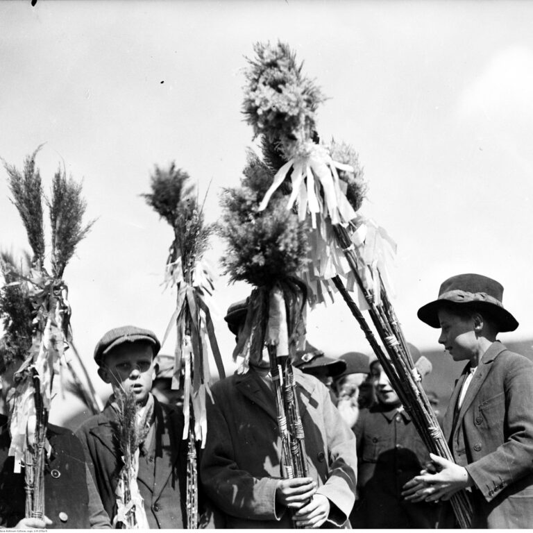 Grupa chłopców w tradycyjnych strojach ludowych trzymających wysokie palmy wielkanocne w Myślenicach, kwiecień 1935 rok. Archiwalna fotografia polskiego folkloru.